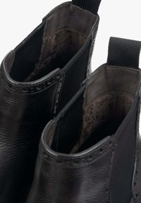 Czarne skórzane botki do kostki z teksturowanym wykończeniem, elastycznymi panelami bocznymi oraz gładką podszewką w miękkim szarym odcieniu.