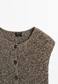 Cardigan senza maniche in maglia marrone e beige con scollo rotondo e tre bottoni scuri sul frontale, etichetta in tessuto di cotone visibile all'interno.