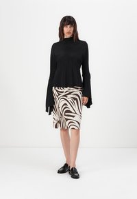 Black long-sleeve top with flared cuffs, paired with a knee-length pencil skirt featuring a brown and white abstract pattern. Black loafers complete the look.