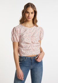 Kortærmet, lyserød blomstret bluse med puffede ærmer, flæse-detaljer og rund halsudskæring, parret med blå denim jeans.