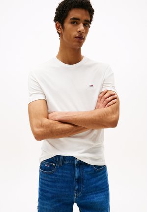 Witte katoenen t-shirt met een ronde hals, korte mouwen, en een klein logo op de linkerborst. Gecombineerd met blauwe denim jeans.