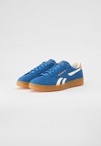 Tenisi bleumarin din suede cu accente albe, suprafață texturată, vârf rotund și talpă din cauciuc caramel. Au sistem de închidere cu șireturi și detalii cu logo.