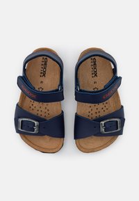 Sandali blu navy con suole in sughero e cinturini perforati. Presentano una fibbia metallica e il marchio Geox, offrendo traspirabilità e comfort.