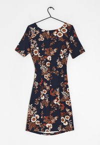 Robe bleu marine jusqu'aux genoux avec des manches courtes et un motif floral marron, blanc et rouge, suspendue à un cintre noir.