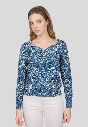 Haut à manches longues bleu et blanc avec un design en V, orné de motifs floraux et d'une ourlet légèrement froncé. Texture de tissu lisse.
