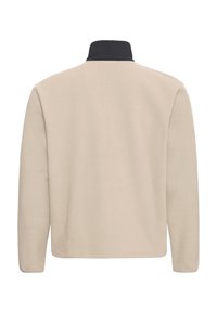 Beige fleecejack met een hoge kraag, voorzien van een zwarte kraagaccent. Glad oppervlak en eenvoudig, recht ontwerp met lange mouwen.