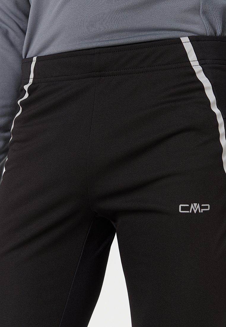 Pantaloni atletici neri con un design aderente, strisce laterali riflettenti e logo CMP. Il materiale sembra liscio ed elastico.