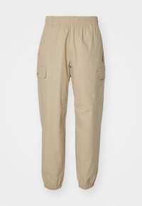 Pantalons cargo beiges avec une taille élastique, des poignets ajustés et deux poches latérales. Le tissu a une texture lisse et un design à jambes droites.