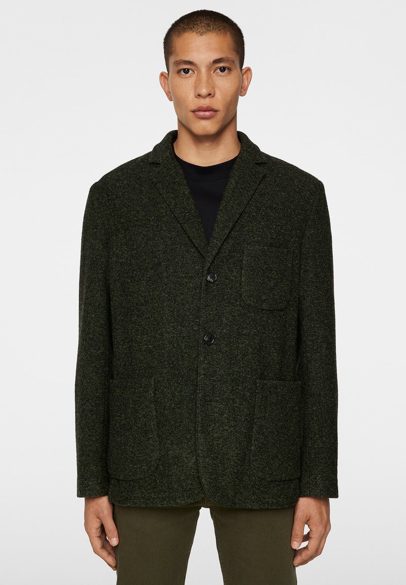 Mörkgrön, texturerad ullblandning blazer med slagkragar, två framfickor och enkelknäppt knappstängning.