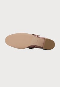 Vue de la semelle d'une chaussure à talons hauts en cuir rose avec semelle texturée, talon bloc et nom de marque "högl" embossé sur la semelle.