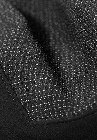 Czarna tkanina z teksturowanym wzorem i białymi plamkami, prezentująca gładką powierzchnię i lekki połysk. Zawiera wykończenie brzegów szytym detalem.