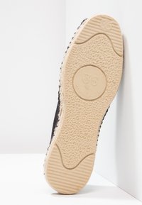 Black shoe sole with a textured surface, featuring a light-colored outsole and embossed size "36." Espadrille-style design with woven accents.