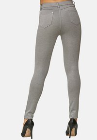 Jeans skinny grigi, con una texture liscia, due tasche posteriori, dettagli di cucitura discreti, abbinati a scarpe con tacco nere.