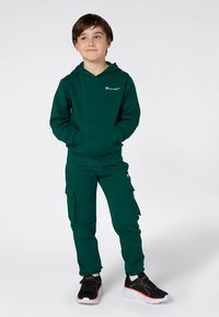 Conjunto de hoodie verde e calças cargo em tecido macio. A hoodie apresenta um bolso frontal e logótipo; as calças têm bolsos laterais e pernas afuniladas.