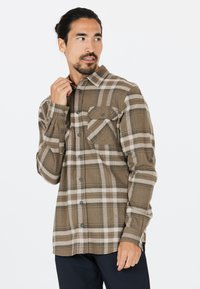 Bruin geruit overhemd met lange mouwen van zachte stof. Beschikt over twee borstzakken en knopen, met een relaxed fit en een button-down kraag.