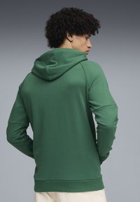 Groene hoodie van een gestructureerde stof, met een trekkoordcapuchon en geribde boorden. Het ontwerp bevat raglanmouwen en een aansluitende taille.
