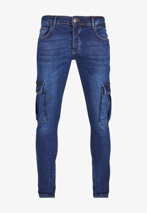 Pantalones cargo de denim en azul oscuro con un diseño ajustado, que presenta bolsillos laterales y una textura desgastada en la tela.