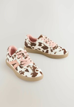 Sæt af low-top sneakers med brunt og hvidt ko-mønster, lyserøde snørebånd, lyserød indvendig og beige gummisåler på en lys baggrund.