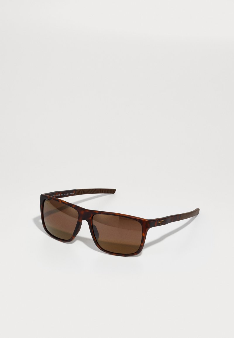 Sunglasses with a tortoiseshell frame, square lenses, and brown tint. Features a textured arm and logo detail on the temple.