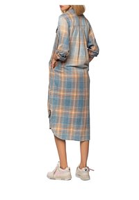 Lång, blå och orange rutigt skjortklänning med uppvaktade ärmar och sidoklyftor; kombinerad med lätta sneakers med rosa inslag.
