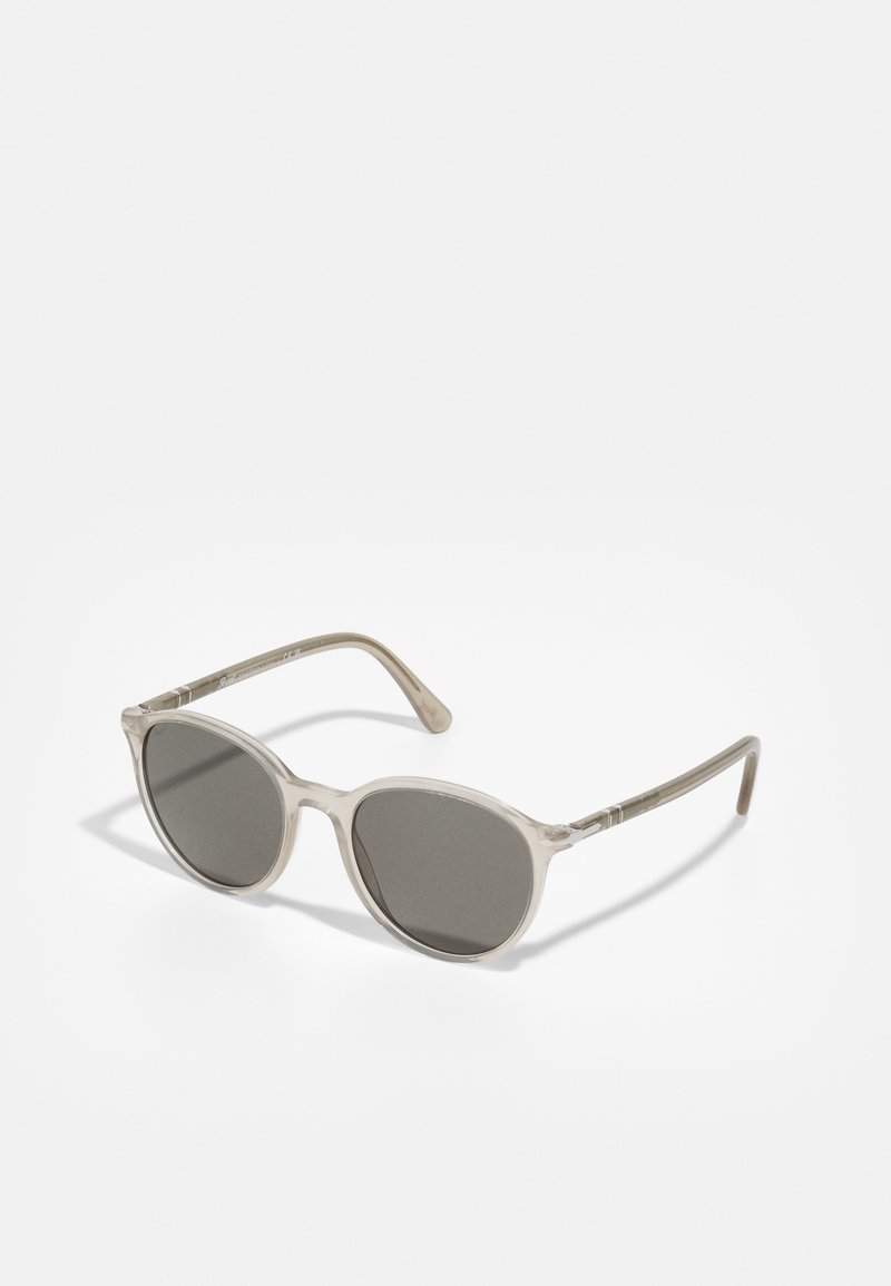Sunglasses med en genomskinlig beige ram, ovala linser med mörk ton och subtila metallaccentuerade bågar.