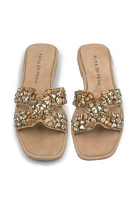 Beige slipper sandalen met een platte zool, met een kruisbandontwerp versierd met metallic en natuurlijke steen versieringen.