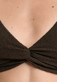 Barna, textúrás bikini felsőrész mély V-nyakkivágással. Középen csavart részlettel és szorosan szőtt anyaggal rendelkezik.