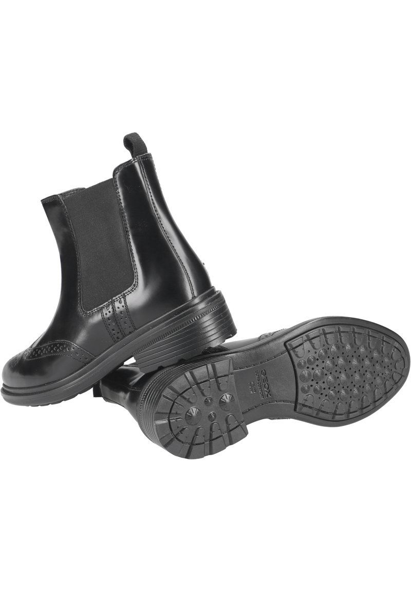 Stivaletti neri in pelle con pannelli elastici laterali, dettagli brogue in evidenza e suole in gomma con motivi di trazione.