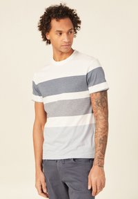 Lyhythihainen T-paita, jossa on vaakasuoria raitoja valkoisena, vaaleansinisenä ja tummansinisenä. Pyöreä kaula-aukko ja normaali istuvuus. Puuvillamateriaali.