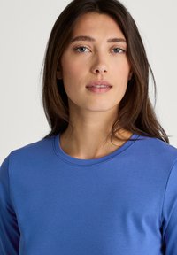 Blauwe longsleeve top gemaakt van een zachte, lichtgewicht stof met een ronde halslijn, met een subtiele textuur en een getailleerde silhoeet.