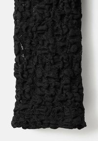 Crna teksturirana pletena šal s neravnomjernim, slojevitim dizajnom koji ima različite debljine, stvarajući vizualno zanimljiv uzorak.