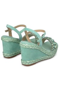 Sandali a zeppa verde menta con upper in materiale sintetico texture, dettaglio in corda intrecciata sulla suola e accenti decorativi in gemme.
