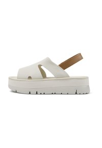 White platform sandals with cut-out design, brown adjustable strap, textured sole, and thick rubber base. Smooth material and elevated heel.