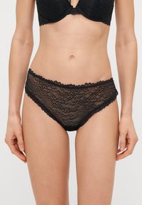 Mustad pitsid lillede mustriga, lainete äärtega ja poolläbipaistva tekstuuriga. Disainitud bikiinistiilis, et saavutada keha järgiv välimus.