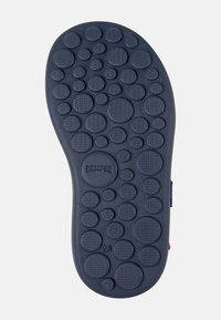 Rubberen schoenzool in marineblauw met verhoogde cirkelvormige patronen, logo-afdruk en reliëfstructuur voor grip en houvast.