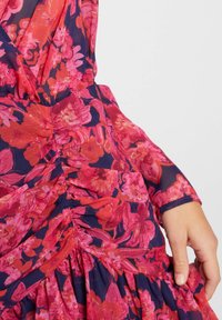 Floral dress with long sleeves, featuring a red and pink flower pattern on a navy background, ruched bodice, and layered skirt.