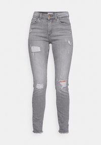 Jeans skinny em denim cinza com detalhes desgastados, apresentando bainhas desfiadas e múltiplos rasgos para um look casual. Fecho de metal com botão e zíper.