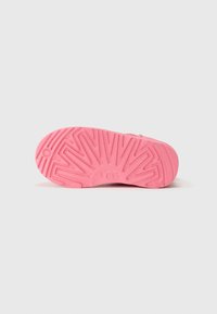 Semelle en caoutchouc rose avec motif de texture et logo "UGG". Forme arrondie et finition lisse ; détail en forme d'étoile près du talon.