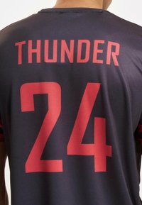 Čierny športový dres s nápisom "THUNDER" tučne vyvedeným červenými písmenami a číslom "24" pod ním, vyrobený z textúrovaného, priedušného materiálu.