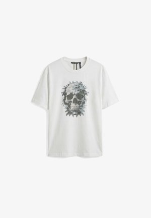 Camiseta blanca de manga corta con un diseño gráfico de una calavera rodeada de hojas de helecho en la parte frontal.