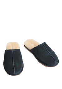 Svarta mocka tofflor med en mjuk beige pälsfoder och rund tå. Har en sömlös ovandel och en platt, flexibel sula.