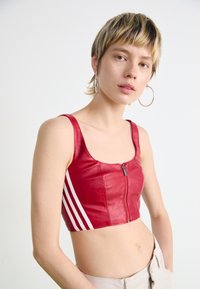 Top cropped vermelho em couro sintético com fecho à frente, apresentando três riscas brancas nas laterais. Textura suave, decote quadrado e alças largas.