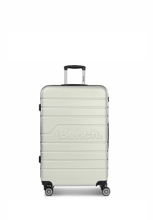 Silver hard-shell suitcase with horizontal ridges, black accents, a retractable handle, and four wheels. "Bench." logo embossed on front.