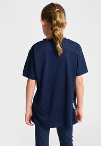 T-shirt à manches courtes bleu marine, avec une coupe ample et un ourlet incurvé. Il présente un logo sur le côté et une texture lisse et douce.