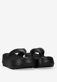 Las sandalias de plataforma negras cuentan con un parte superior de piel sintética suave, dos correas gruesas y una suela de goma texturizada para mayor tracción.