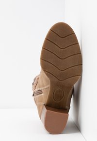 Brązowy boot z teksturowanego zamszu, gumową podeszwą z bieżnikiem oraz delikatnym obcasem. Zamek błyskawiczny po boku.