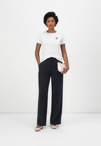 White cotton t-shirt with red "LOVE" embroidery, paired with navy high-waisted wide-leg trousers and light pink handbag.