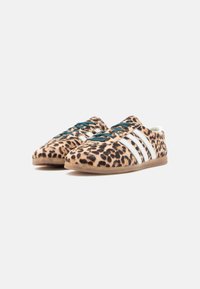 Αθλητικά παπούτσια με σχέδιο λεοπάρδαλης, πράσινα κορδόνια, λευκές ρίγες, μαλακή υφή και ελαφριά καφέ λαστιχένια σόλα, σχεδιασμένα για καθημερινή χρήση.