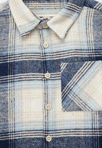 Flanellhemd mit blau-cremefarbenem Karo-Muster, Button-Down-Kragen und einer Brusttasche im passenden Karodesign.