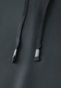 Tessuto tecnico nero con un design testurizzato e perforato. I lacci del cappuccio presentano accenti grigi alle estremità.